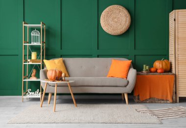 Kanepesi, raf ünitesi ve sonbahar dekoru olan rahat bir oturma odası.