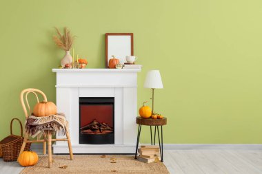 Odanın içinde şömine, balkabağı ve sandalye var.