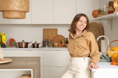 Mutfakta sonbahar süslemeleriyle güzel genç bir kadın.