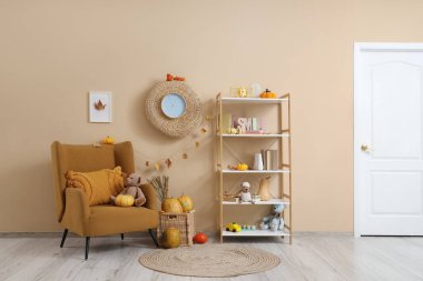 Koltuklu, raflı ve balkabaklı çocuk odasının içi.