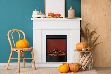 Beyaz şömine, sonbahar oturma odasında tahta kütükler ve balkabaklarıyla dolu sepet.