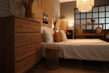 Yatak, çekmece, raf ünitesi ve yatak odasının içinde parlayan lamba.