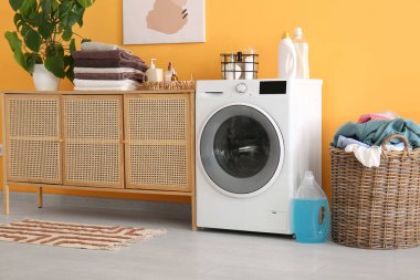 Modern çamaşır makinesi, çekmeceler ve çamaşır sepeti.
