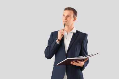 Takım elbiseli düşünceli bir işadamı, arka planda not defteri var.