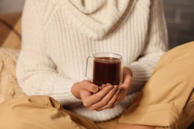 Bir fincan sıcak çikolatalı güzel kadın akşam evde oturuyor, yakın plan.