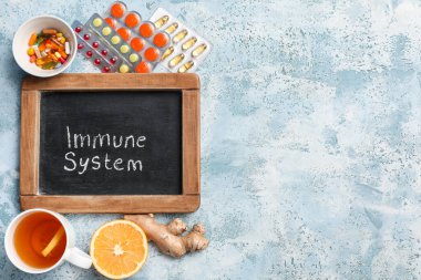 IMMUNE Sistemleri, haplar, bir fincan çay, turuncu ve zencefil kökü içeren yazı tahtası