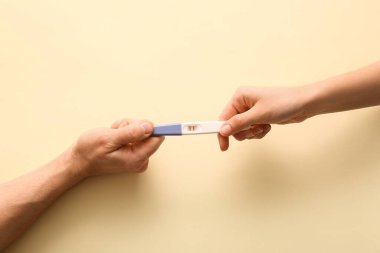 Bej arka plan üzerinde hamilelik testi yapan çift, üst görünüm