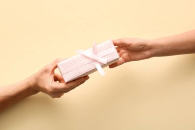 Bej arka planda hediye kutusu olan çift, üst görünümde.