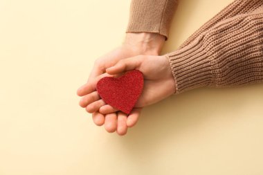 Bej arka planda kırmızı kalp taşıyan çift, üst görünüm