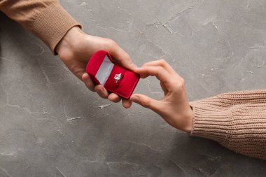 Grunge arka planında nişan yüzüğü tutan çift, üst görünümde.