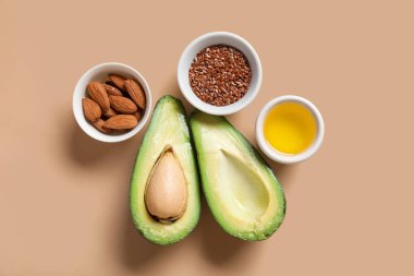 Arkaplanda badem, keten tohumu, yağ ve taze avokado bulunan kaseler