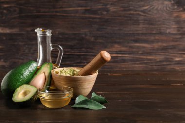 Taze avokado, koyu ahşap arka planda püre ve yağ dolu kâseler.