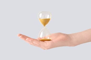 Gri arka planda kum saati olan kadın eli. Zaman yönetimi kavramı