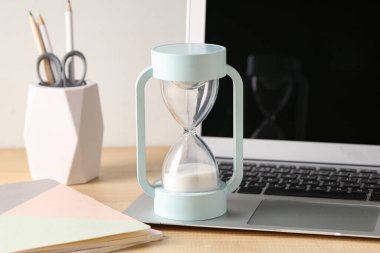 Hourglass and laptop on table. Time management concept