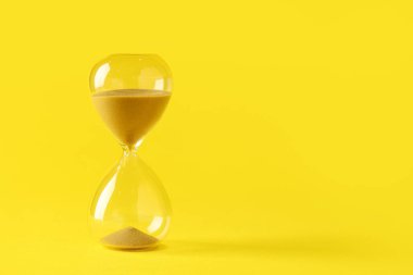 Sarı arka planda kum saati. Zaman yönetimi kavramı