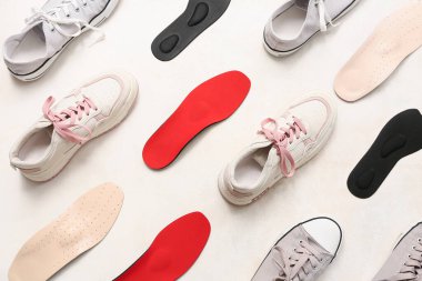 Açık arkaplanda ortopedik tabanlı farklı ayakkabılar.