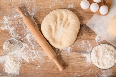 Merdaneli taze hamur, un ve yumurtalar ahşap masada.