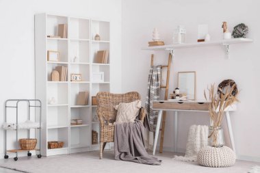 Odanın içi masa, hasır koltuk ve kış dekoruyla aydınlık.