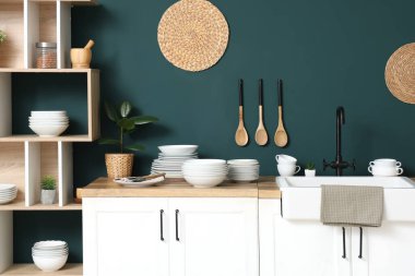 Mutfağın içinde mavi duvarın yanında farklı plakalı tezgahlar var.