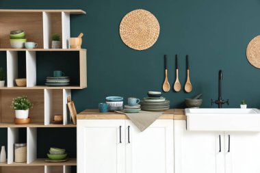 Mutfağın içinde mavi duvarın yanında farklı plakalı tezgahlar var.