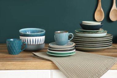 Mutfakta mavi duvarın yanında farklı tabaklar olan tahta masa.