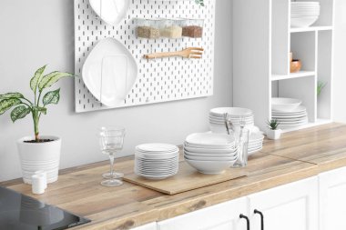 Tabaklar, kaseler ve bardaklar mutfaktaki beyaz duvarın yanındaki masada.