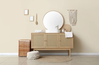 Çekmeceler ve çamaşır sepeti şık banyodaki bej duvarın yanında.