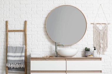 Çekmeceler ve merdiven beyaz tuğla duvarın yanında şık bir banyoda.