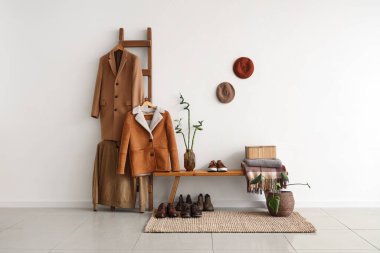 Beyaz duvarın yanında giysileri olan banklı ve merdivenli modern salonun içi.