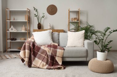 Rahat bir kanepe, puf ve çiçekli rahat bir oturma odası.