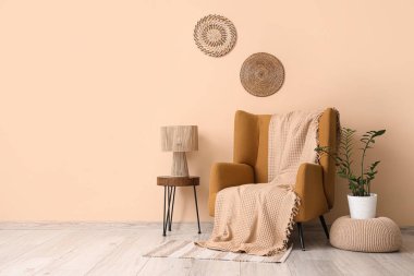 Kahverengi koltuk, puf ve masa, odanın içindeki bej duvarın yanında.