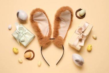 Paskalya yumurtalı tavşan kulakları ve bej arka planda hediye kutuları.