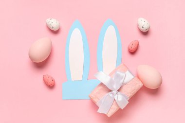 Paskalya yumurtaları ve pembe arka planda hediye kutusu olan kağıt tavşan kulakları.