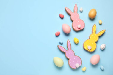 Mavi arka planda Paskalya yumurtaları olan tahta tavşanlar.