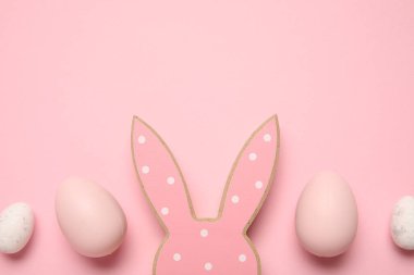 Pembe arka planda Paskalya yumurtaları olan tahta tavşan kulakları.