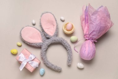 Paskalya yumurtası ve bej arka planda hediye kutusu olan tavşan kulakları.