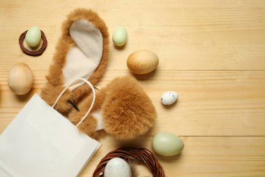 Tavşan kulaklı alışveriş torbası ve hafif ahşap arka planda Paskalya yumurtası.