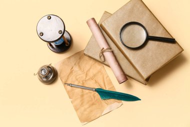 Kitaplı eski kağıt çarşaf, tükenmez kalem, mürekkep hokkası, parşömen ve bej arka planda büyüteç