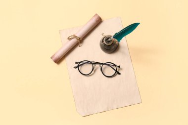 Bej arka planda kalem, mürekkep, kaydırma ve gözlüklü eski kağıt çarşaf