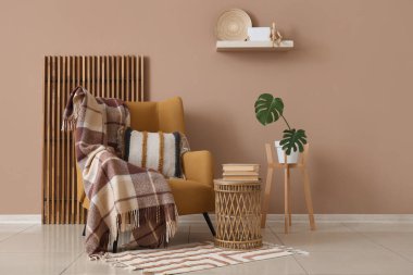 Katlanan ekran, koltuk ve odada kahverengi duvarın yanındaki Monstera bitkisi.