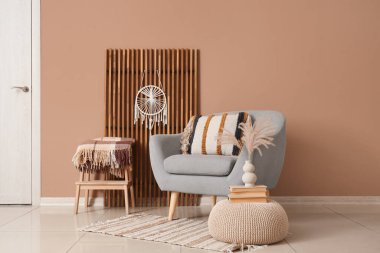 Katlanan ekran, koltuk ve puf kahverengi duvarın yanında.