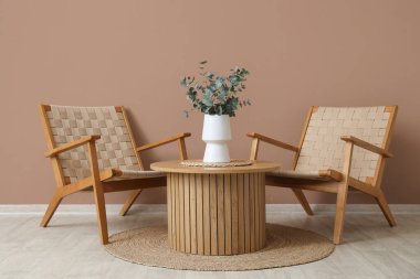 Hasır koltuklar ve kahverengi duvarın yanındaki masa.