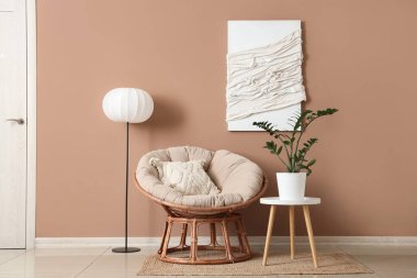 Oda içinde lamba, rahat koltuk ve kahverengi duvarın yanındaki bitki örtüsü.