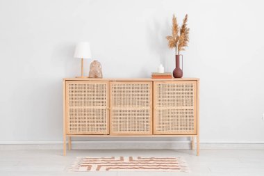 Kitaplı lamba ve şık ahşap çekmeceler üzerine dekorasyon odası beyaz duvarın yanında.