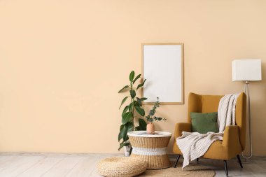 Koltuk, okaliptüslü kahve masası vazoda bej duvarın yanında çiçek.