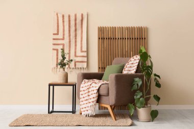 Koltuk, ekose, yastık ve okaliptüs dalları olan bir vazo. Odadaki beyaz duvarın yanındaki sehpanın üzerinde.