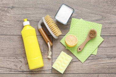 Kabartma tozu, paçavra, temizlik fırçası, sünger ve limon dolu bir şişe deterjan.