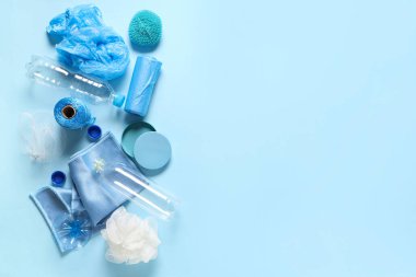 Boş plastik şişeler, çöp torbaları, mikrofiber, süngerler ve mavi arka planda farklı kapaklar.