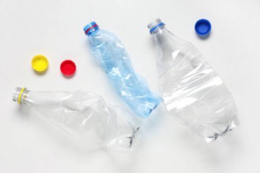 Kırışmış plastik şişeler ve beyaz arka plan kapakları.