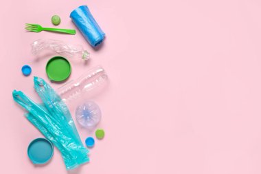 Farklı kapaklı plastik şişeler, çöp torbaları ve pembe arka planda çatal.